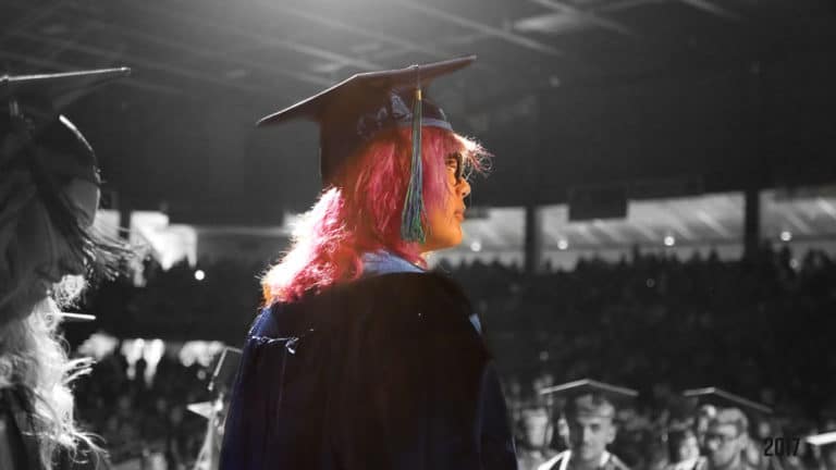 Graduate with pink hair going on stage to get diploma