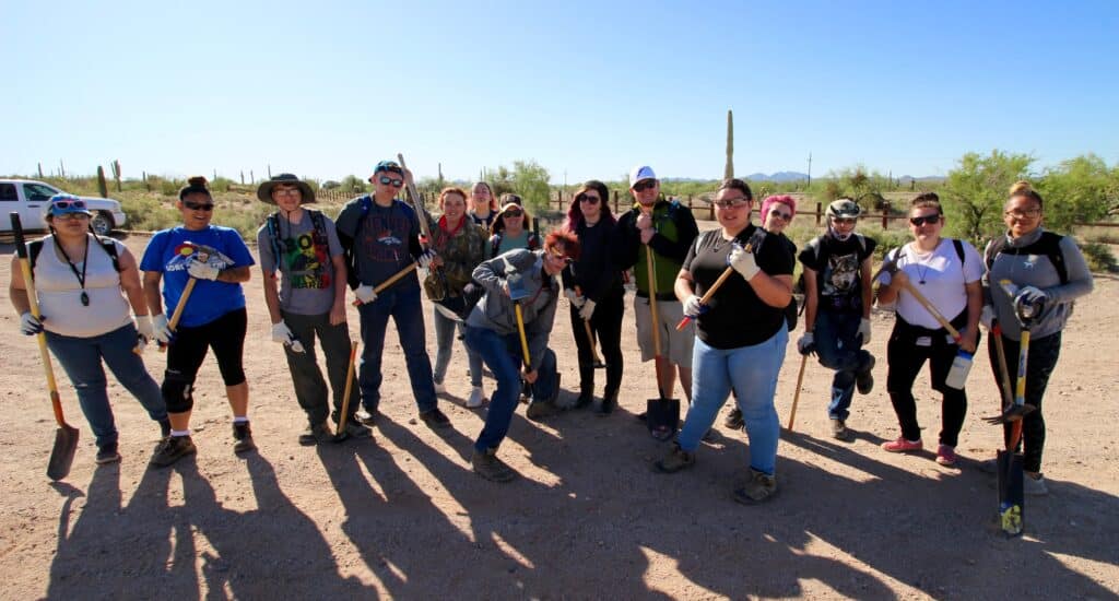Group of students in the desert holding tools.