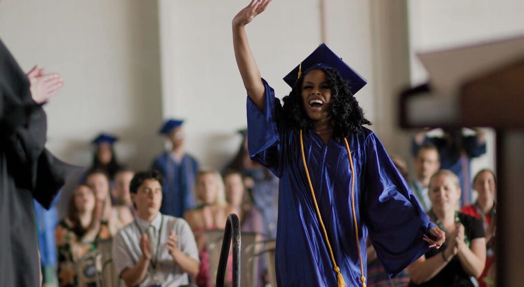 Student Celebrating While walking on the stage to receive their diploma.
